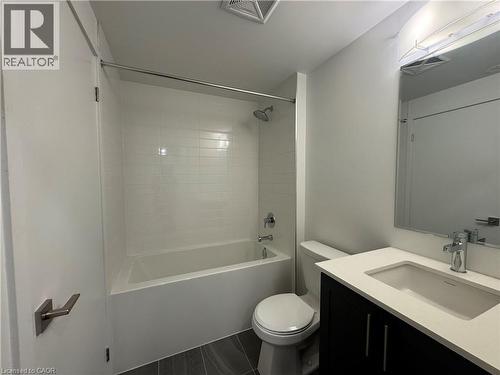 Full-size bathtub with a subway tile surround, dark wood-finish vanity with a light countertop, and a wall-mounted mirror with integrated lighting - 17 Lytham Green Circle Unit# 27, Newmarket, ON 