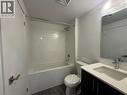 Full-size bathtub with a subway tile surround, dark wood-finish vanity with a light countertop, and a wall-mounted mirror with integrated lighting - 17 Lytham Green Circle Unit# 27, Newmarket, ON 