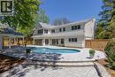 White exterior residence featuring a curved swimming pool, extensive paver patio, stone retaining wall, and a covered outdoor pavilion - 130 Edgecliffe Place, Halton, ON 