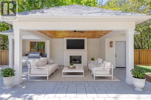 Covered outdoor living space featuring a brick fireplace, wood-finish ceiling, built-in outdoor kitchen, and a ceiling fan - 130 Edgecliffe Place, Halton, ON 
