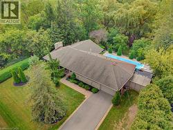 Expansive property featuring a paved driveway, mature trees, a manicured lawn, and an in-ground swimming pool - 