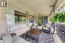 Covered porch with stone column, wood-paneled ceiling, and a dark entry door - 1316 Nevarc Drive, Burlington, ON 