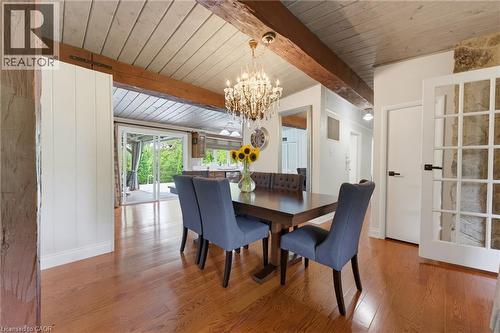 Wood-finish flooring, exposed wood beams, vaulted planked ceiling, sliding glass doors, and a chandelier with a metallic finish - 1316 Nevarc Drive, Burlington, ON 