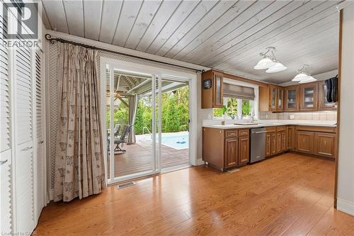 Kitchen featuring wood-finish flooring, wood cabinetry with glass-front uppers, stainless steel dishwasher, and a white countertop - 1316 Nevarc Drive, Burlington, ON 