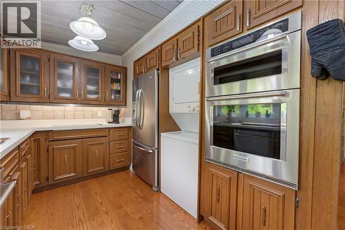 Kitchen featuring wood-finish flooring, white countertops, tile backsplash, and stainless steel appliances including a built-in double oven and refrigerator - 1316 Nevarc Drive, Burlington, ON 