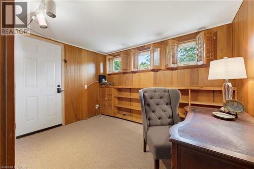 Recessed windows with wood shutters, wood paneling, built-in shelving, white panel door, and carpeted flooring - 1316 Nevarc Drive, Burlington, ON 