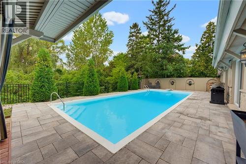 Rectangular swimming pool with integrated steps, surrounded by paver stone hardscaping - 1316 Nevarc Drive, Burlington, ON 