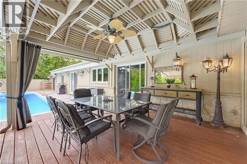 Expansive covered outdoor living area with a wood-finish deck, ceiling fan, and slatted ceiling - 1316 Nevarc Drive, Burlington, ON 