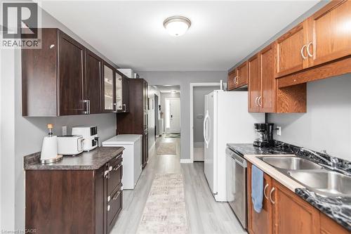 Galley kitchen featuring dual-tone cabinetry, laminate countertops, and stainless steel sink - 42 Saturn Road, Port Colborne, ON 