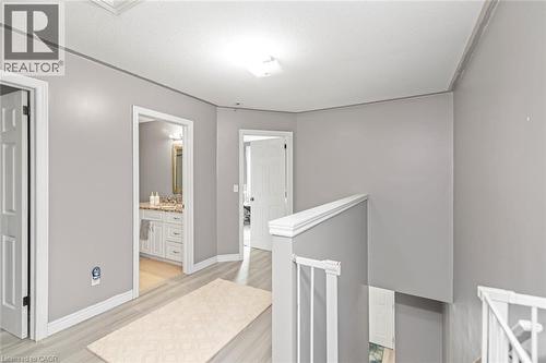 Hallway with wood-finish flooring, white doors, and a bathroom vanity featuring a light-toned countertop - 42 Saturn Road, Port Colborne, ON 