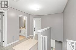 Hallway with wood-finish flooring, white doors, and a bathroom vanity featuring a light-toned countertop - 