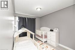 Light gray walls, recessed ceiling light, window with dark curtains, and light wood-finish flooring - 