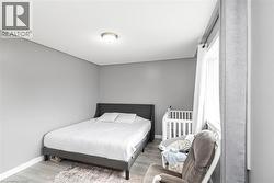 Recessed ceiling light fixture, neutral gray wall paint, light-toned wood-finish flooring, and white window trim - 