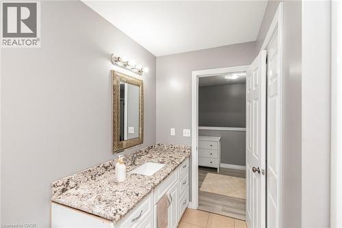 Vanity with an integrated sink, granite countertop, white cabinetry, and brushed nickel light fixture - 42 Saturn Road, Port Colborne, ON 
