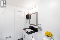 Vanity with black countertop and integrated sink, wall-mounted mirror, and bi-fold doors - 