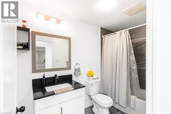 Bathroom with dark speckled countertop, white vanity, black faucet, framed mirror, and a tiled shower surround - 