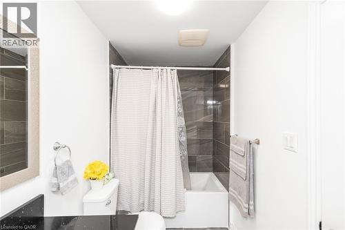 Bathroom featuring a white bathtub, dark-toned wall tiling, white toilet, and a vanity with a dark countertop - 42 Saturn Road, Port Colborne, ON 