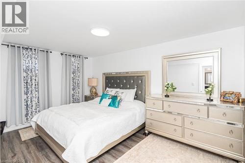 Wood-finish flooring, recessed ceiling light, white walls, mirror with a metallic frame, and a dresser featuring multiple drawers - 42 Saturn Road, Port Colborne, ON 