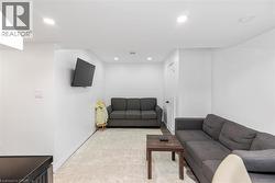 Recessed lighting, wood-finish flooring, white walls, and a white door with dark hardware - 