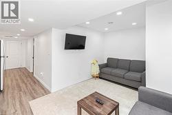 Recessed ceiling lighting, wood-finish flooring, white walls, and a white interior door with black hardware - 