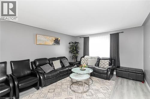 Light grey walls with white trim, a large window with dark grey drapes, and wood-finish flooring - 42 Saturn Road, Port Colborne, ON 