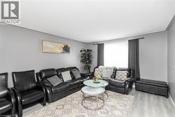Light grey walls with white trim, a large window with dark grey drapes, and wood-finish flooring - 