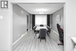 Recessed lighting, light gray wood-finish flooring, white trim, and a contemporary ceiling fixture - 
