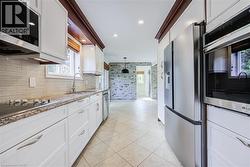 Kitchen featuring white cabinetry, stainless steel appliances, a tile backsplash, and a built-in microwave - 