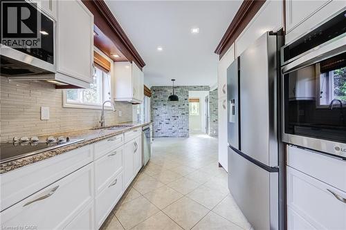 Kitchen featuring white cabinetry, stainless steel appliances, a tile backsplash, and a built-in microwave - 3148 Terraview Court, Burlington, ON 
