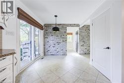 Tiled flooring throughout, featuring a stone accent wall, white paneled door with matte black hardware, and a sliding glass door with a Roman shade - 