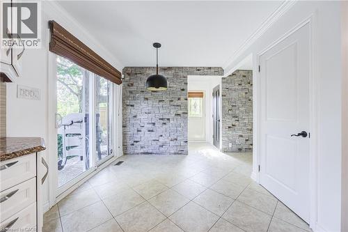 Tiled flooring throughout, featuring a stone accent wall, white paneled door with matte black hardware, and a sliding glass door with a Roman shade - 3148 Terraview Court, Burlington, ON 
