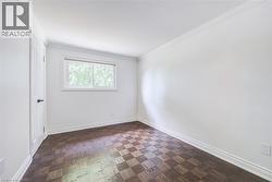 Wood-finish parquet flooring, white walls, crown molding, and a window with white trim - 