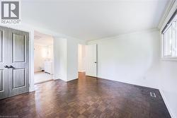 Dark wood-finish flooring with a parquet pattern, white painted walls, and a window with white trim - 
