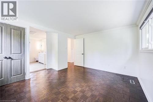 Dark wood-finish flooring with a parquet pattern, white painted walls, and a window with white trim - 3148 Terraview Court, Burlington, ON 