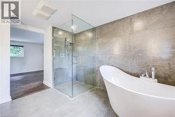 Expansive bathroom featuring a freestanding soaking tub, a walk-in shower with a glass enclosure, an integrated shower bench, and floor-to-ceiling wall tiling - 