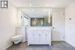 White shaker vanity with a single basin, wall-mounted floating toilet, and large rectangular mirror - 