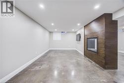 Recessed lighting, wood-finish accent wall, built-in fireplace, concrete flooring, and white trim - 