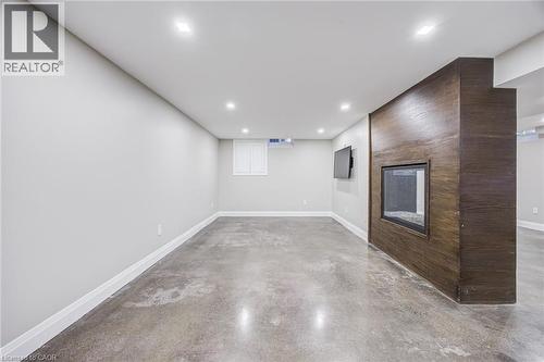 Recessed lighting, wood-finish accent wall, built-in fireplace, concrete flooring, and white trim - 3148 Terraview Court, Burlington, ON 