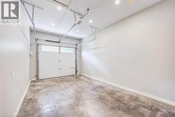 Concrete flooring, white walls, overhead garage door system, recessed lighting, and a white garage door with windows - 