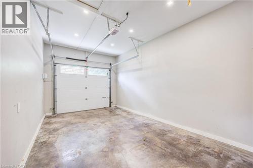 Concrete flooring, white walls, overhead garage door system, recessed lighting, and a white garage door with windows - 3148 Terraview Court, Burlington, ON 