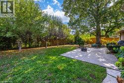Expansive backyard with a concrete patio, mature trees, and natural landscaping - 
