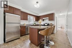 Full kitchen featuring wood-finish cabinetry, stainless steel appliances, stone-finish countertops, and a kitchen island with seating - 