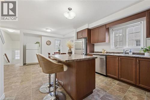 Kitchen featuring wood cabinetry, stainless steel appliances, a center island with seating, and tile flooring - 931 Glasgow Street Unit# 27B, Kitchener, ON 