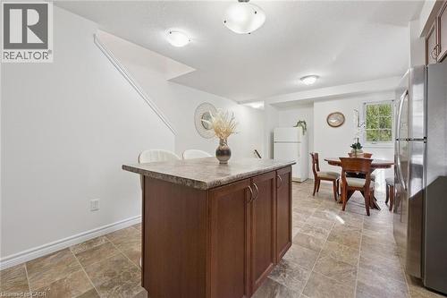 Kitchen island with dark wood-finish cabinetry and a stone-look countertop - 931 Glasgow Street Unit# 27B, Kitchener, ON 