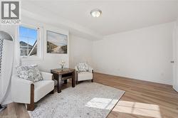 Light-toned wood-finish flooring, white walls, and a window with white trim - 