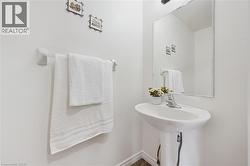 Pedestal sink with a chrome faucet, wall-mounted mirror, and tile flooring - 