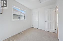 Carpeted room with a white framed window, two panel doors, and a ceiling hatch - 