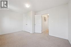 Neutral-toned carpeting, white walls, and a flush mount ceiling light fixture - 