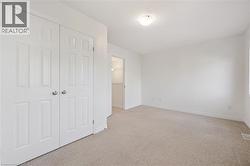 Neutral tone carpeted flooring, white walls, flush mount ceiling light fixture, bi-fold closet doors with round hardware, and white trim - 
