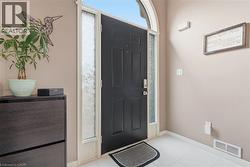 Arched transom entry with a paneled door, decorative frosted glass sidelights, and white tile flooring - 